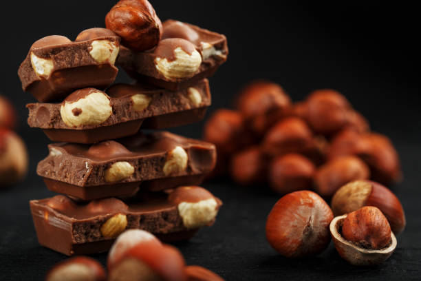 istock Chocolate with hazelnuts in the form of a tower on a dark background, surrounded by nuts in the shell and peeled. 1272207272
