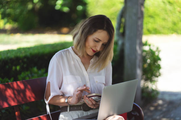 Beautiful Smiling Lady using Laptop and Phone in a Park