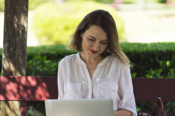 istock Beautiful Smiling Lady using Laptop in a Park 1272208443