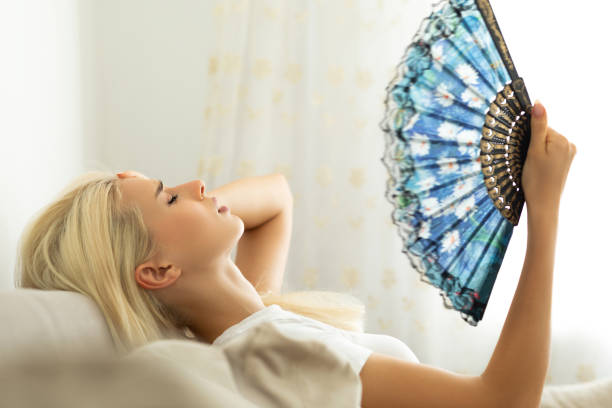 Woman feeling hot waving fan annoyed with high temperature Woman feeling hot waving fan annoyed with high temperature overheated photos stock pictures, royalty-free photos & images