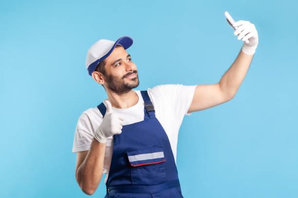 istock Satisfied courier in overalls talking on video call, showing thumbs up, using mobile phone for communication 1272208696