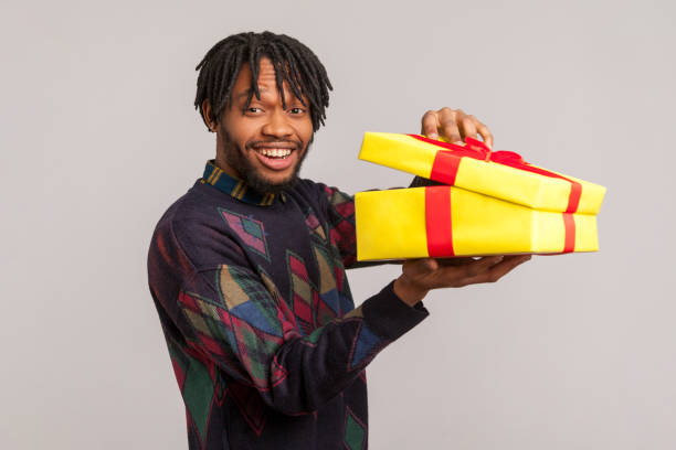 istock Pleased smiling african man with dreadlocks looking at camera holding in hands unboxed gift, completely surprised and satisfied with present 1272208798