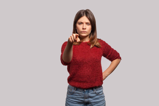 Hey you! Portrait of angry bossy woman in shaggy sweater pointing finger to camera, looking with suspicion Hey you! Portrait of angry bossy brunette woman in shaggy sweater pointing finger to camera, looking with suspicion and accusing, choosing guilty. indoor studio shot isolated on gray background scolding stock pictures, royalty-free photos & images