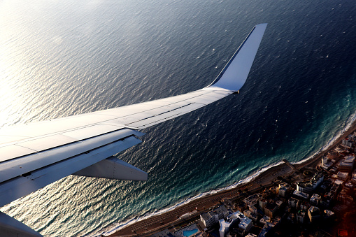 Airplane wing flying above greek town