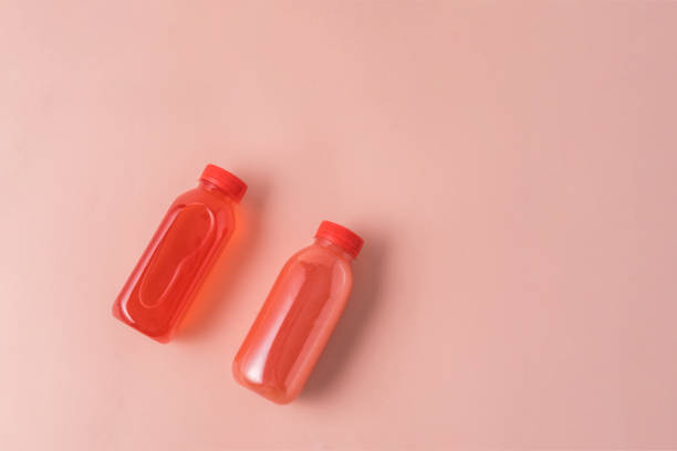 The healthy fruit juice drink in Eco bottles on pink background. Minimal style. Zero waste. Copy space.