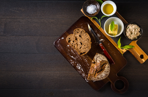 Tuna spread with fresh bread slice, sage butter, olive oil and salt on rustic wooden table.