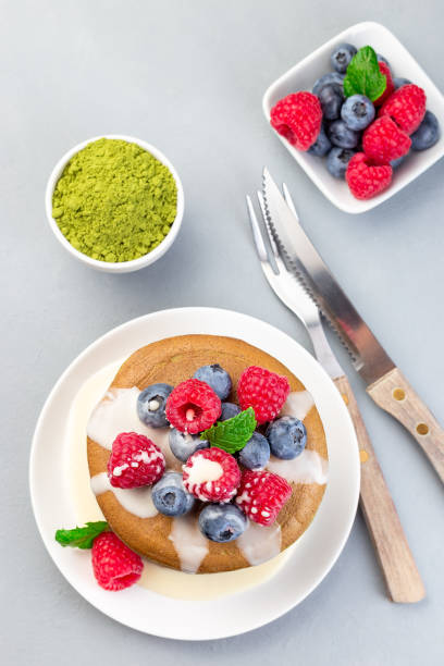 istock Stack of matcha pancakes served with condensed milk, blueberry and raspberry on white plate, vertical, top view 1272222200