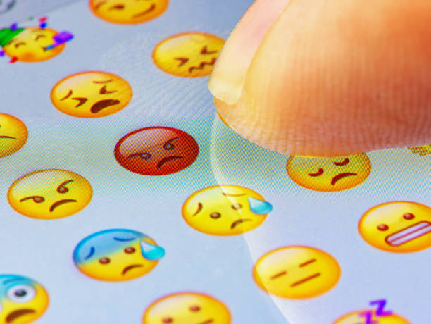 Macro finger touching angry emoji on a virtual keyboard