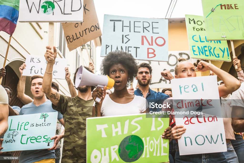 Activists demonstrating against global warming Group of activists is protesting outdoors - Crowd demonstrating against global warming and plastic pollution, concepts about green ecology and environmental sustainability Protest Stock Photo