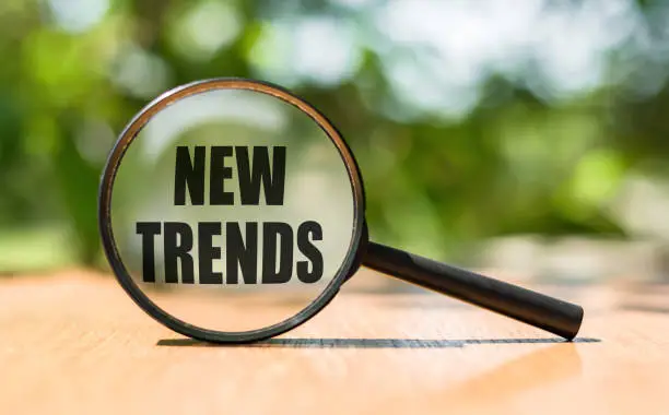 Photo of NEW TRENDS text written on magnifying glass. Main trend of changing something. Popular and relevant topics. New trends in business. Recent and latest trend. Evaluation methods.