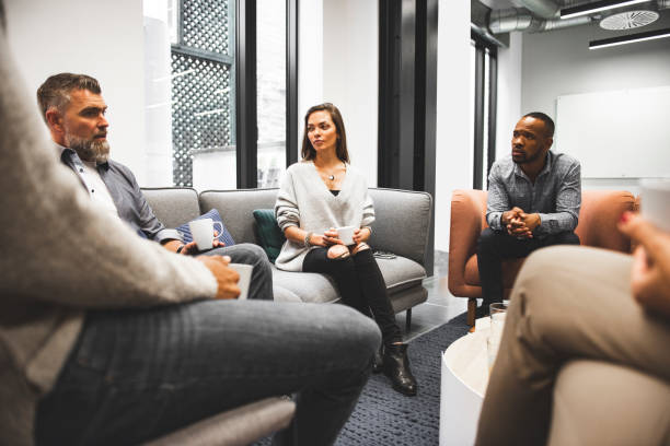 Group of business people in office cafeteria, on coffee break, chatiing, drinking coffee