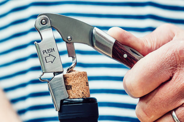 Pleasant evening ahead Close up of the removal of a cork from a wine bottle. The opener is the type which lifts the cork in two stages. cork stopper stock pictures, royalty-free photos & images