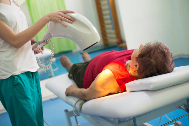 Old woman on physical therapy Old woman on the physical therapy with light in the medical clinic. light therapy stock pictures, royalty-free photos & images