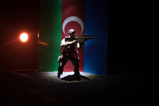 Azeri army concept. Silhouette of armed soldiers against Azerbaijani flag. Creative artwork decoration. Military silhouettes fighting scene dark toned foggy background. Selective focus