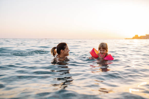 bambina di tre anni che nuota in mare imparando a nuotare, indossando ali d'acqua - women courage water floating on water foto e immagini stock