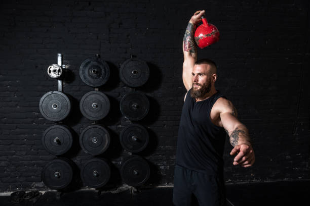 istock Young sweaty strong muscular fit man with big muscles doing hardcore cross kettlebell snatch workout training in the gym 1272245587