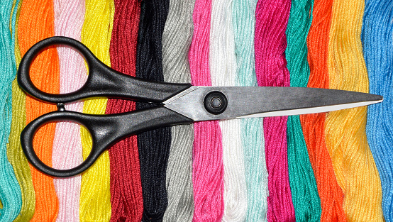 Black scissors on multi-colored skeins of floss. Choosing a color for needlework