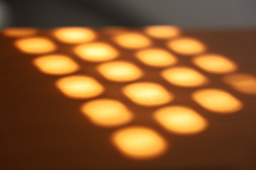 Sunbeam like shadows of a window onto a table surface with a glass