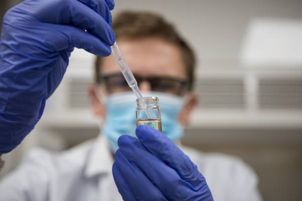 científico que trabaja en un laboratorio de química analítica. manos enguadas con una pipeta y tubos de ensayo para analizar una muestra - gloved hand fotografías e imágenes de stock