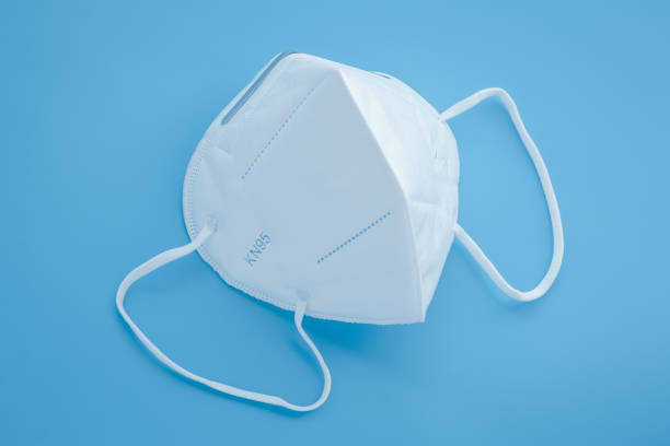 Surgical KN95 respirator, white protective medical face mask to cover the mouth and nose. Blue background. Covid-19 prevention, protection concept from oronavirus disease pandemic. Surgical KN95 respirator, white protective medical face mask to cover the mouth and nose. Blue background. Covid-19 prevention, protection concept from oronavirus disease pandemic n95 face mask photos stock pictures, royalty-free photos & images