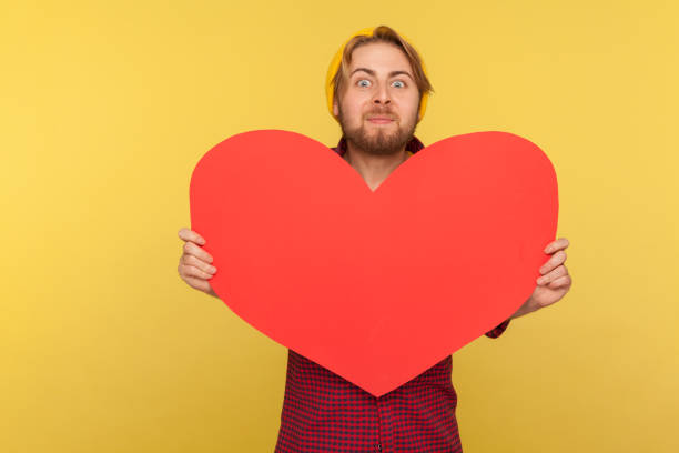 istock Romantic guy holding big read heart and looking at camera with excitement, demonstrating love affection feelings 1272252505