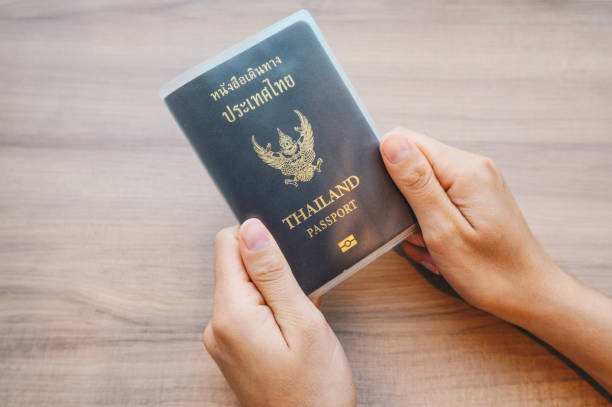 istock Someone hands holding a Thailand passport in book cover before take a flight. 1272255010