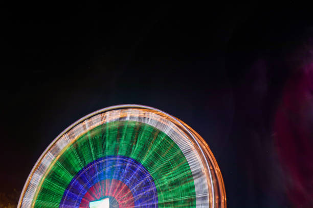 遊園地でライトで夜に回転するフェリーホイール。 - ferris wheel wheel blurred motion amusement park ストックフォトと画像