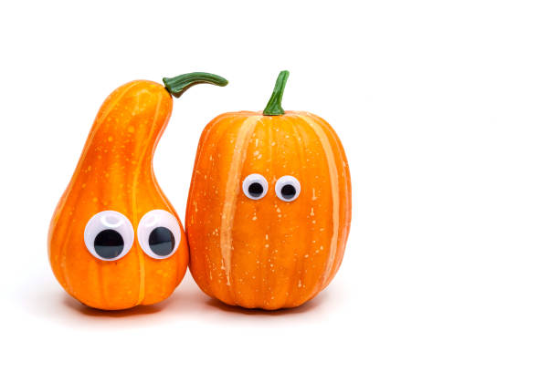 Two cute decorative pumpkins with eyes on an isolated white background. Thanksgiving and halloween day concept Two cute decorative pumpkins with eyes on an isolated white background. Thanksgiving and halloween day concept pumpkin decorating stock pictures, royalty-free photos & images