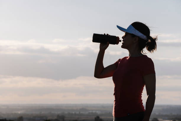istock woman drinking water from a bottle against the light 1272257106