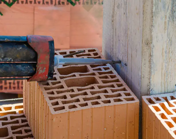 Anchoring of the masonry in the pillar for the anti-seismic prescription. With an electric drill, the hole for anchoring the steel bar to the reinforced concrete structure is made