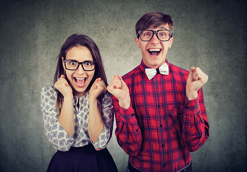 Casual young man and woman with funny expression screaming with excitement looking at camera.