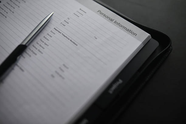 istock Filling out a form with personal information. Documents in a folder on the table to fill. Handwritten information about the applicant. 1272259961