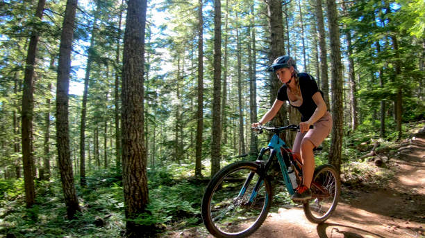 istock Female mountain biker rides along forested path 1272260814