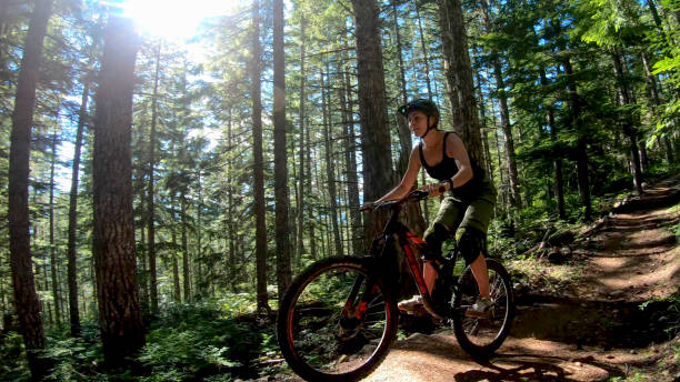 istock Female mountain biker rides along forested path 1272260984