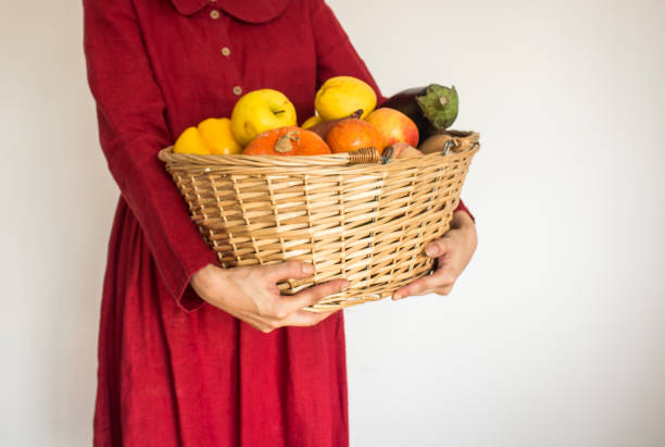 mujer con vestido de lino rojo sosteniendo cesta con frutas. - agriculture autumn apple greengrocers shop fotografías e imágenes de stock