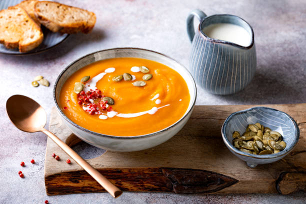 Vegetarian autumn pumpkin and carrot soup with cream, seeds and spices. Fall and winter comfort, healthy slow food stock photo