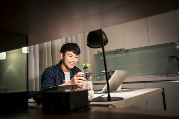 自宅で働くアジア人男性 - オール電化 1人暮らし ストックフォトと画像