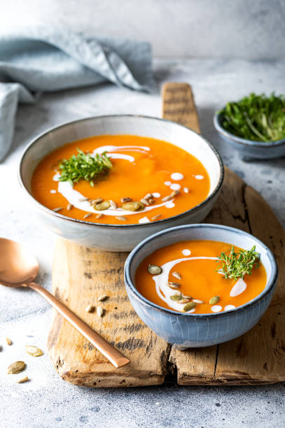 Vegetarian autumn pumpkin and carrot soup with cream, seeds and cilantro micro greens. Comfort food, fall and winter healthy slow food concept stock photo
