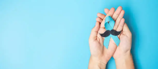 Photo of November Prostate Cancer Awareness month, adult Man holding light Blue Ribbon with mustache for supporting people living and illness. Healthcare, International men, Father and World cancer day concept
