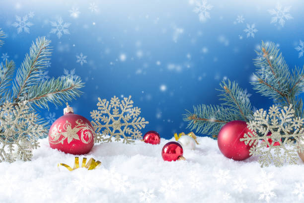 istock Christmas ornaments on snow over blue background with snowflakes. 1272272379