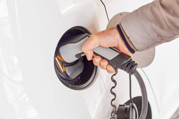 istock Man using a power cable and plug for charging of electric car at EV charging station. 1272272974