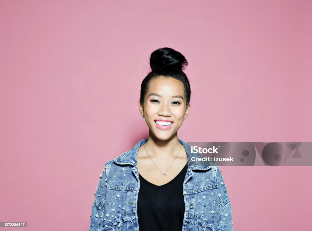 Confident smiling businesswoman on pink background Portrait of smiling confident businesswoman. Female entrepreneur standing against pink background. She is wearing denim jacket. Colored Background Stock Photo