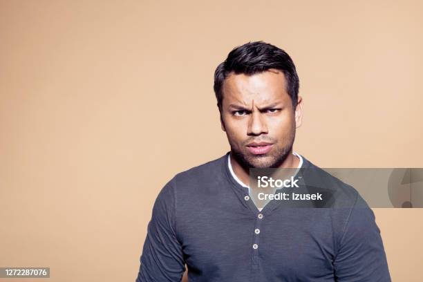Suspicious Businessman Over Brown Background Stock Photo - Download Image Now - Colored Background, Men, Spanish and Portuguese Ethnicity