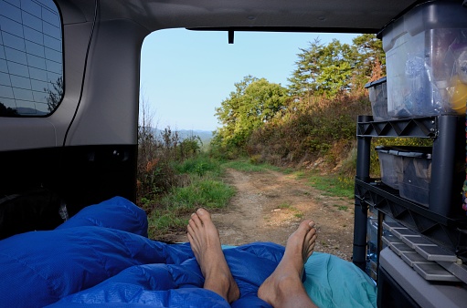 Resting in bed in back of overland vehicle and enjoying scenic view through open tailgate