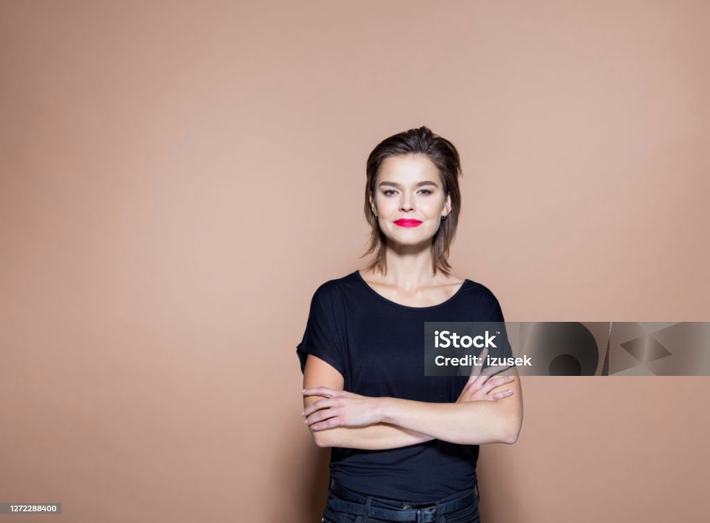 Smiling businesswoman against pink background Portrait of confident entrepreneur with arms crossed. Smiling businesswoman standing against pink background. She is in casuals. 20-24 Years Stock Photo