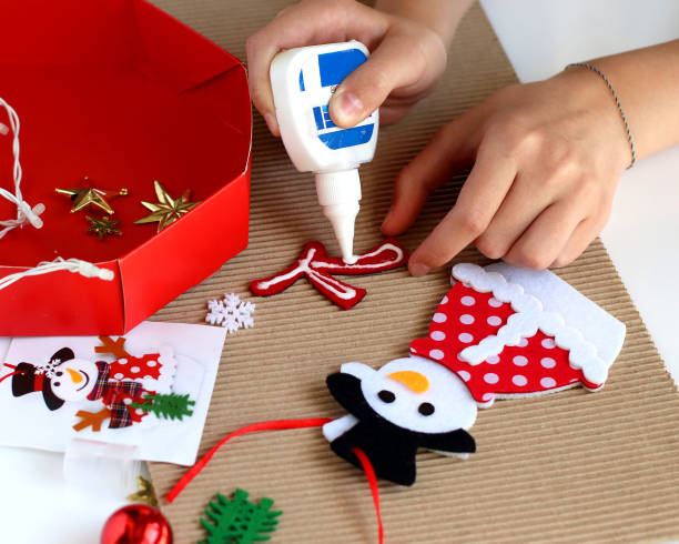 istock Getting ready for Christmas. Children's hands collect Christmas tree toy Snowman. Tools for work are on the table. Getting ready for Christmas 1272290746