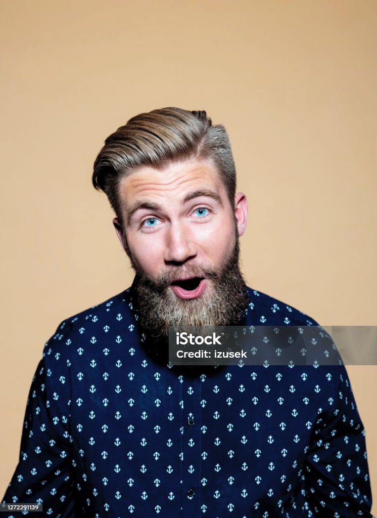 Surprised businessman against brown background Portrait of surprised entrepreneur with mouth open. Smiling businessman standing against brown background. He is wearing blue shirt. Portrait Stock Photo