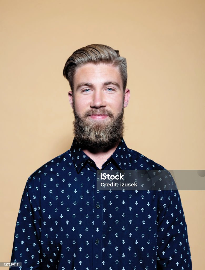 Smiling entrepreneur standing on brown background Portrait of smiling entrepreneur. Confident businessman standing against brown background. He is wearing casual shirt. 25-29 Years Stock Photo