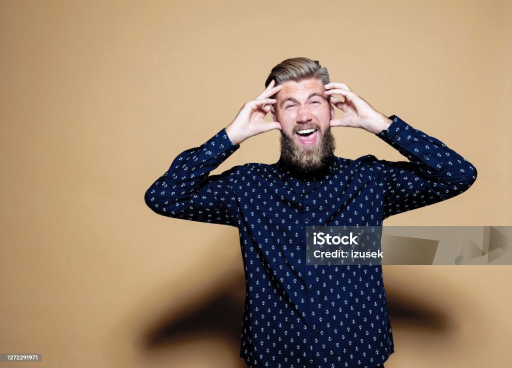 Frustrated businessman against brown background Portrait of frustrated businessman with head in hands. Confused male entrepreneur standing against colored background. He is in casual blue shirt. Entrepreneur Stock Photo
