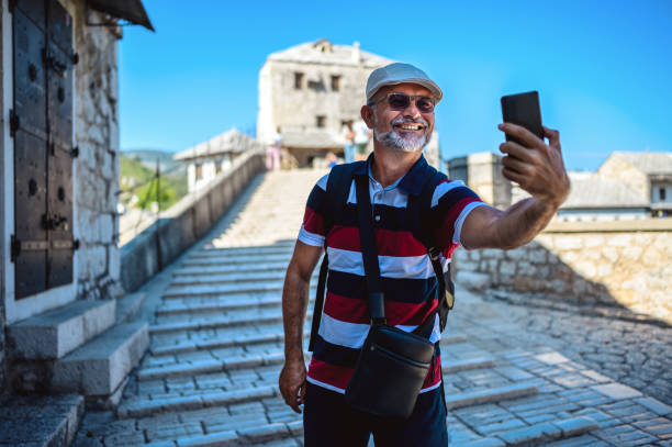 Mature male tourist taking a selfie at the Old Bridge, Mostar, Bosnia and Herzegovina. Mature male tourist taking a selfie at the Old Bridge, Mostar, Bosnia and Herzegovina. stari most mostar stock pictures, royalty-free photos & images